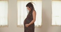 Pregnant woman holding and looking down at her belly.