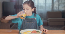 Young girl enjoying a glass of orange juice.