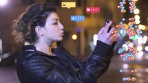 Girl taking selfies with animated social media emojis on the side of her.