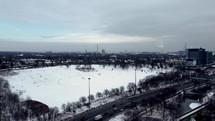 Aerial view of Riverdale Park East in dynamic urban scenario in Toronto on a winter day. Aircraft flying right above Don Valley Parkway while people slide on the snow. Drone does an orbit movement.