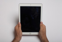Hands holding an electronic tablet on a white background.