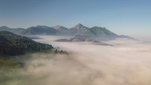 Fly over foggy mountains country in sunny morning
