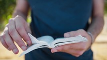 Religious Believer In Christ Man Is Leafing Through The Gospel Outside In Park