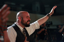 a man with raised hands at a worship service 