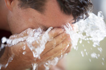 Man splashing his face with water in his hands.