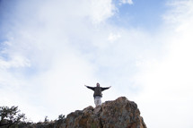 a man standing at the top of a cliff with open arms 