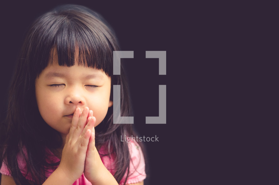 Little asian girl praying in the morning.Little asian girl hand praying,Hands folded in prayer concept for faith,spirituality and religion.Black background.