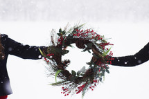women holding a Christmas wreath 