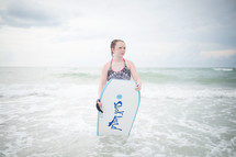 a girl on a beach with a boogie board 