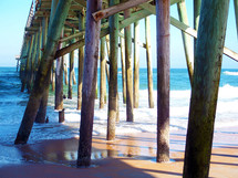 The Ocean view from under a fishing pier off the coast of Florida where the ocean meets the sea shore at Saint Augustine Beach in Florida. 