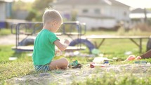 Boy plays sand toys outdoors. Little sweet boy playing in sandbox on playground. Child playing in the sandbox with toy. Happy family healthy children concept.