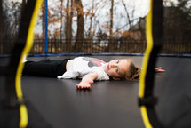 a little girl lying on a trampoline 