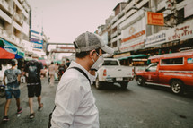 a man wearing a face mask walking on a street 