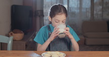 Young girl drinking a glass of milk at home.