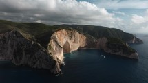 Aerial hyperlapse Navagio Shipwreck Beach Zakynthos Greece, turquoise water surrounded by tall sea cliffs with scenic clouds in background