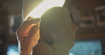 Close up of an old sculptor working on a clay sculpture in his small studio