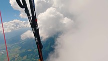 Paragliding pilot flying in fluffy storm clouds and turning fast in summer mountains adrenaline adventure extreme sport
