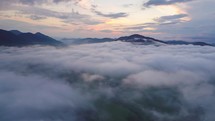 Aerial time lapse flight above mist clouds over beautiful evening nature colors hyperlapse
