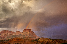 rainbow over a red mountain peak 