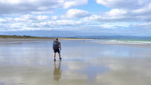 Men walking on ninety mile beach in New Zealand ocean coast landscape in summer
