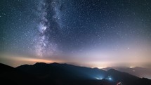 Starry night sky in mountains Astronomy Time lapse, Milky way galaxy stars motion over countryside traffic