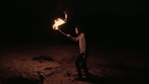 a man standing in darkness holding a glowing torch of fire 