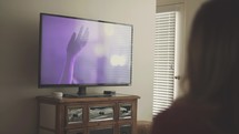 a woman watching a worship service on her tv