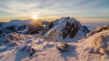 Colorful golden sunset in snowy mountains in winter above mist clouds. Dolly shot time-lapse day to night
