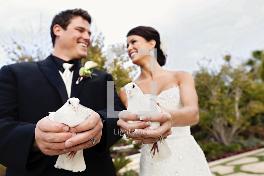 Bride and groom holding doves wedding day release love smiling laughing