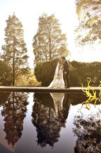 A bride and groom kiss next to a pond