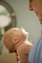 man holding and looking at a newborn