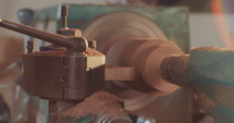 Slow motion macro shot of a man working on a wood lathe creating art.