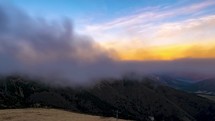 Time-flapse of Misty mountains with foggy clouds on mountain range in peaceful spring evening nature Panorama
