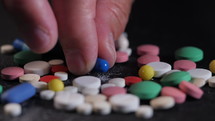 Grandmother counts multicolored tablets on black table at home. The concept of old age, medication, treatment. Close-up of hands with wrinkles.