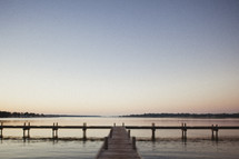 A dock out in the lake at sunset