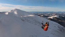 Free paragliding flight above snowy alpine mountains in winter landscape

