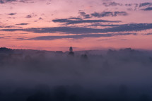 morning mist over a lake at sunrise and distant steeple 