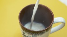 Pouring steaming fresh natural milk into a mug for breakfast 