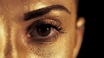 Macro View Of Woman's Face With Beautiful Golden Body Art Looking To Camera