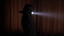 A Girl is Holding a Flashlight While Examining the Dark Room - Medium Shot	