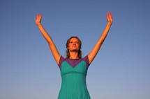 a young woman with arms raised in worship