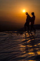 a couple walking atop Pamukkale in Turkey at sunset 