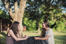teen girls talking and laughing sitting at a picnic table 
