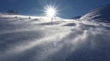 Windy day in winter alpine mountains, wind blowing snow in frozen nature
