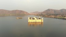 Serene Jal Mahal (Water Palace) laying in the middle of the Man Sagar Lake in Jaipur, Rajasthan, India - Aerial wide Panoramic orbit shot