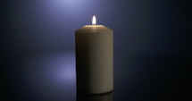 Slow motion close up footage of a white candle on a dark background