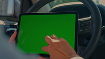 woman scrolling isolated green screen using gadget sitting in the car traveling by car in summer
