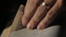 man turning the pages of a Bible 