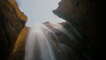 looking up at a rushing waterfall over a cliff 