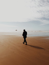 Silhouette of a man walking along the beach.